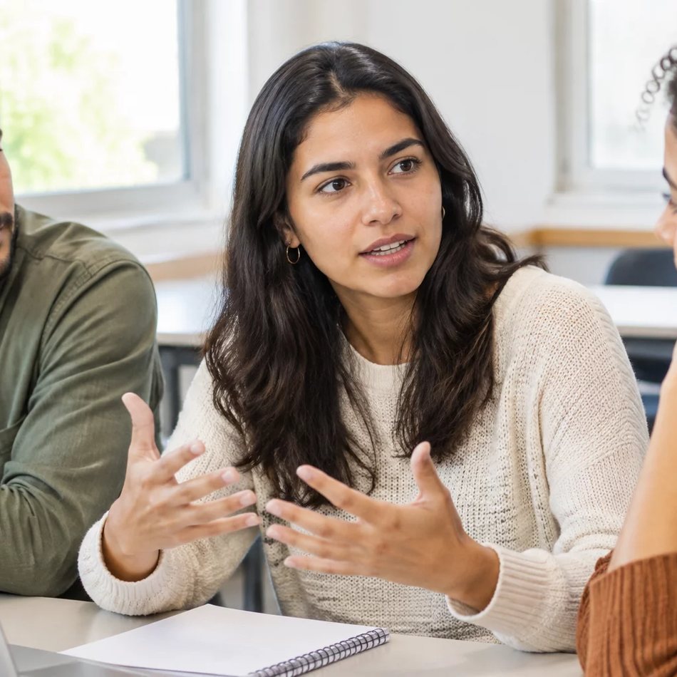 Duas participantes conversando de pé entre as estantes de uma biblioteca